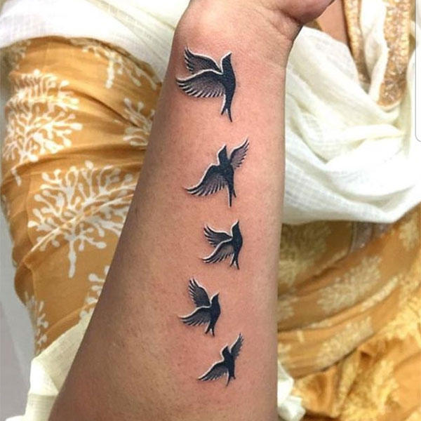 Group of birds flying on wrist tattoo