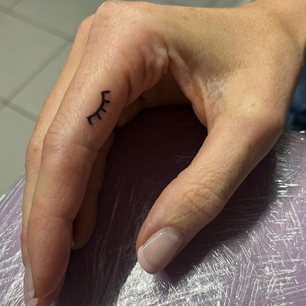 Tiny eyelash tattoo on finger