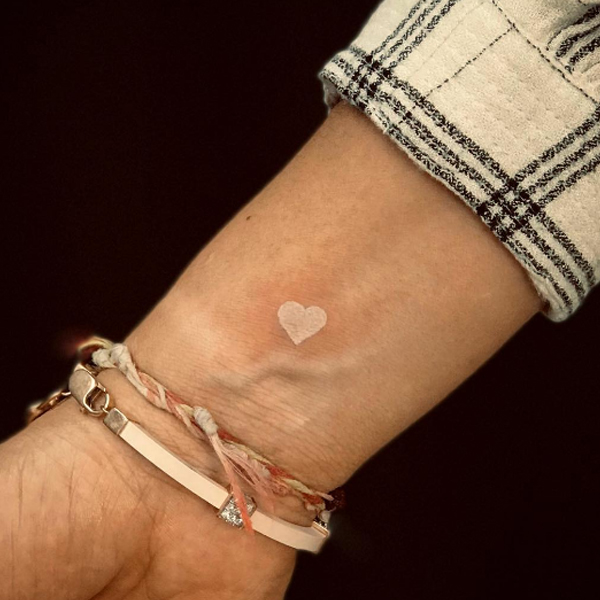 Tiny cute white color heart tattoo on the wrist